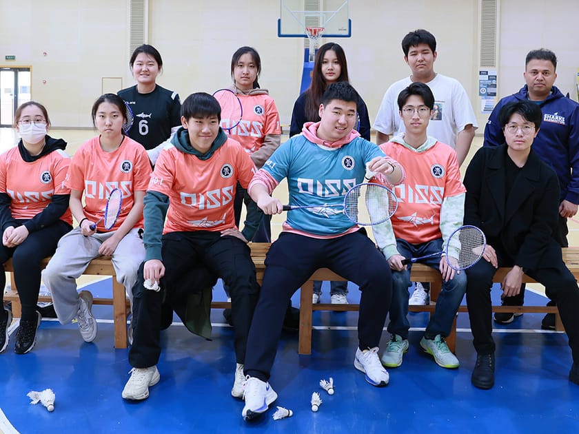 Extracurriculars That Strengthen College Applications 2 QISS high school badminton team poses together in uniform, illustrating sustained athletic commitment built year by year