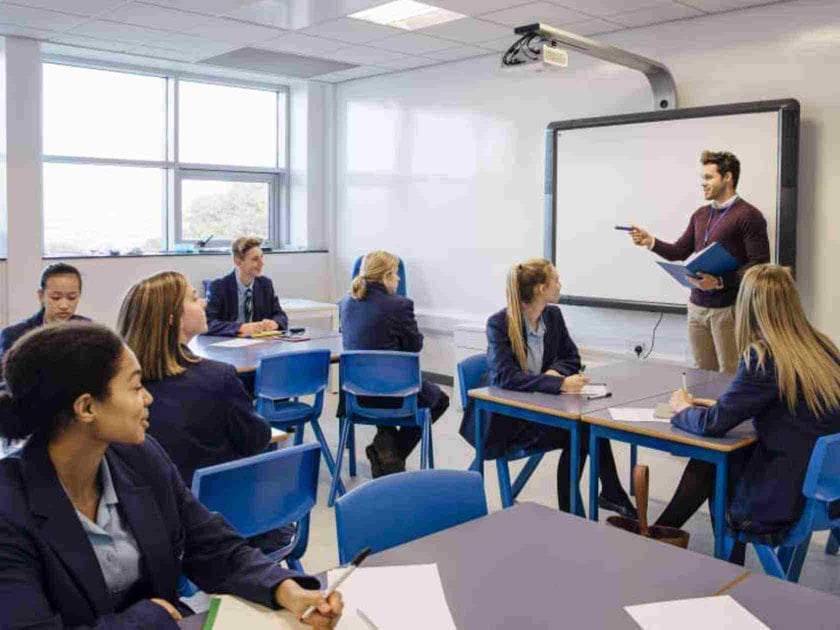 Middle school students engage in a teacher-led lesson in a modern QISS classroom, reflecting the bilingual academic environment.