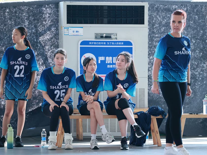 Diversity and Inclusion in International Schools 1 A diverse group of middle-school students in matching Sharks uniforms sitting together on a gymnasium bench, representing inclusion in an international school community