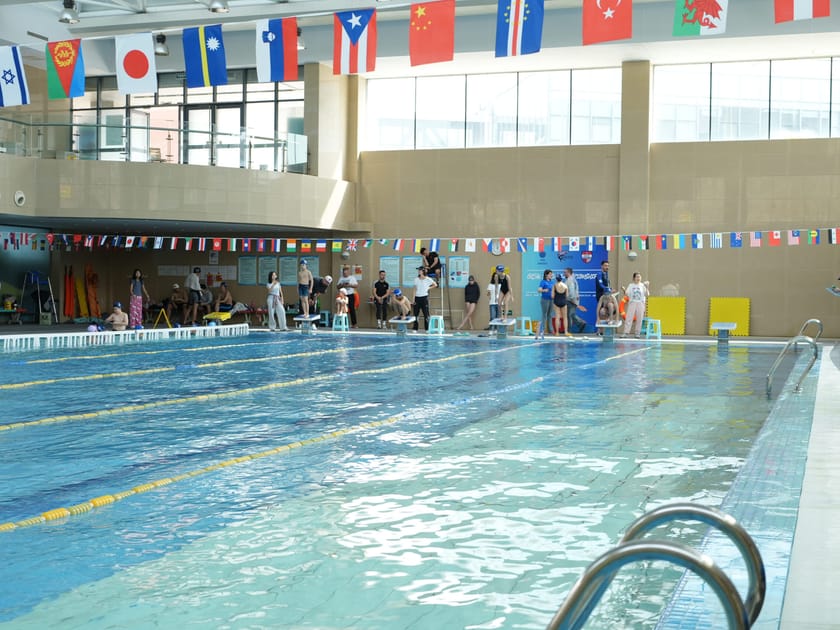 International Mindedness: How Schools Raise Global Citizens 1 Students lined up at an indoor pool beneath international flags at QISS, symbolising the school's multicultural community