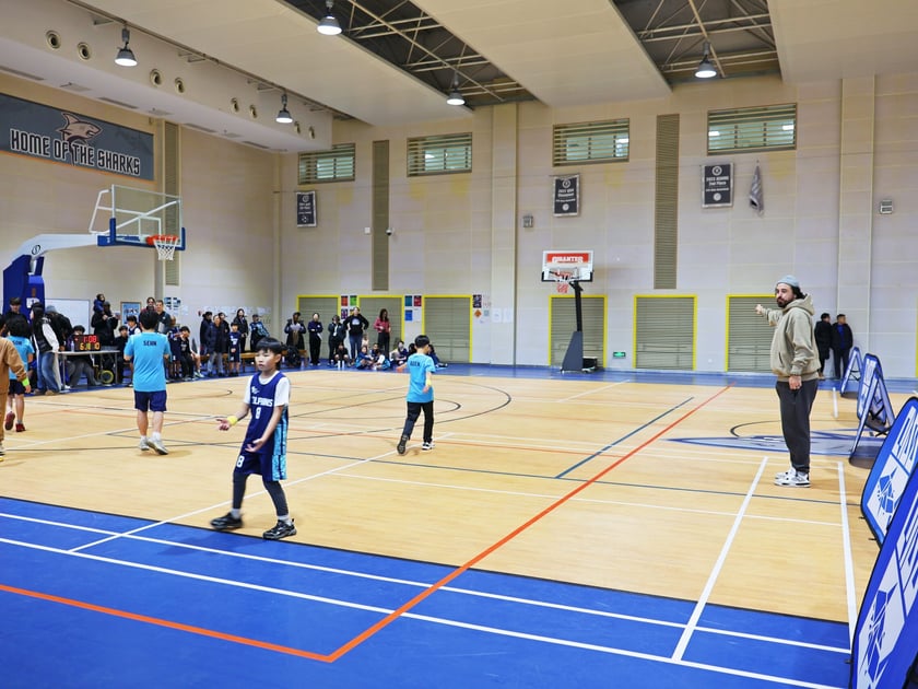 International Mindedness: How Schools Raise Global Citizens 3 Lower-school students competing in a basketball tournament at QISS with classmates cheering from the sidelines