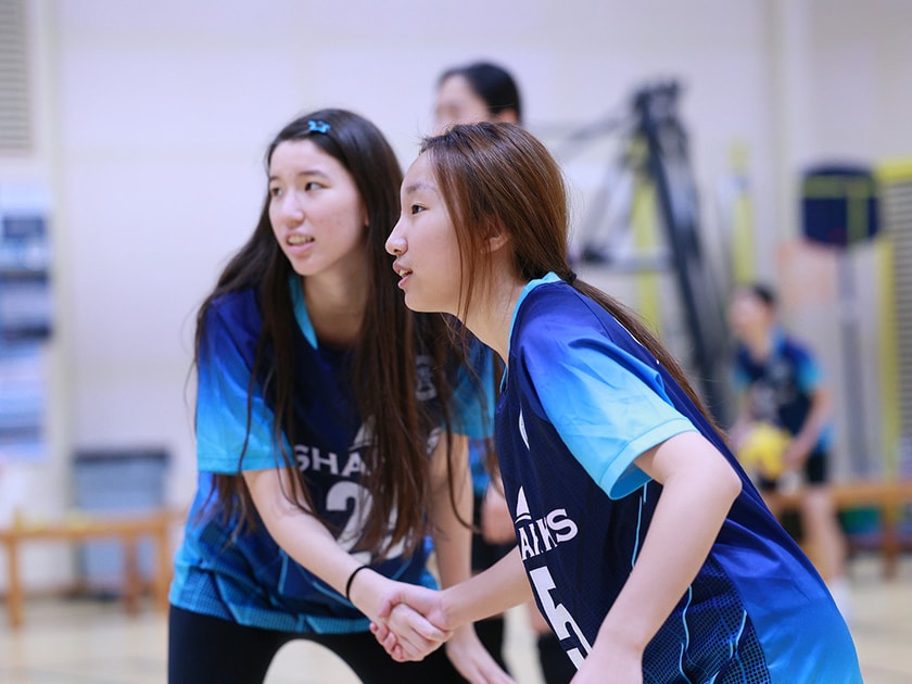 Social Emotional Learning: How Schools Build Resilience 1 Two middle school girls in volleyball uniforms hold hands and smile, showing peer connection and emotional support during a school game