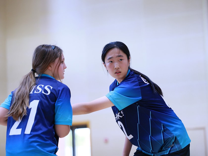 Student Wellbeing in Schools: What Actually Works 1 Two middle school students in volleyball uniforms share a supportive moment, one placing a hand on the other's shoulder during a game