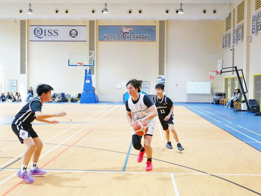 After School Activities: What the Research Says 1 Middle school students playing basketball in the QISS gymnasium during an after-school sports program, with spectators cheering from the sidelines