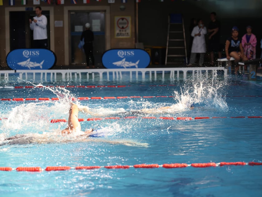 After School Activities: What the Research Says 2 A student swimmer competes in a freestyle race at an indoor school swim meet, illustrating athletic commitment and achievement through extracurricular programs