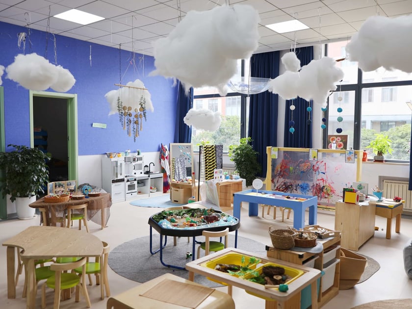 Bright early-childhood classroom with natural wood furniture and colourful learning stations illustrating a safe school environment