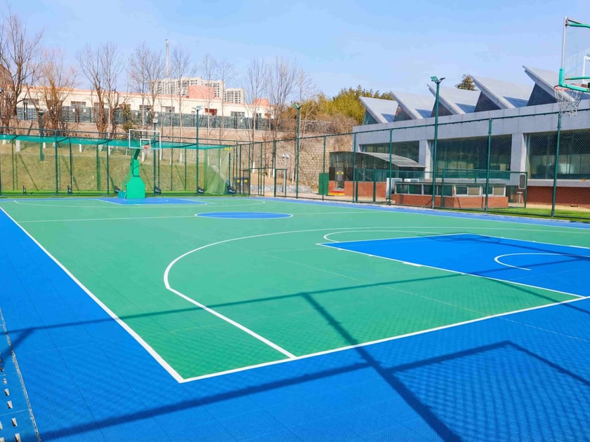 Competitive Sports in School: Building Excellence Beyond the Score 3 Modern outdoor multi-sport courts with blue and green playing surfaces on the QISS campus