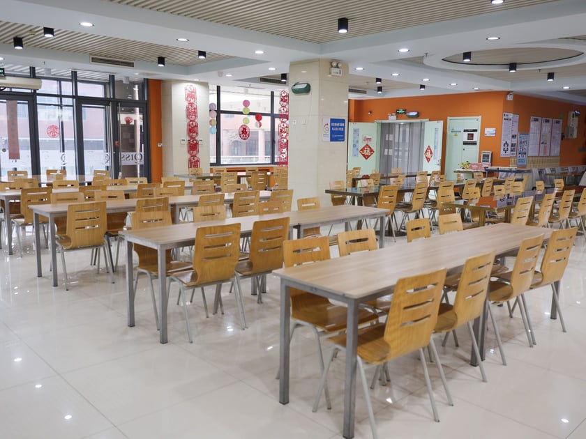 International School Admissions: A Parent's Roadmap 2 Bright modern school cafeteria at QISS with wooden chairs, long tables, and large windows — a space parents see during admissions visits