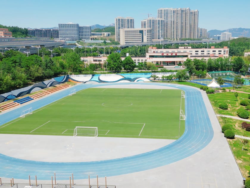 School Athletics Programs: Sports for Every Student 1 Aerial view of QISS athletic complex showing soccer field, blue running track, and sports facilities