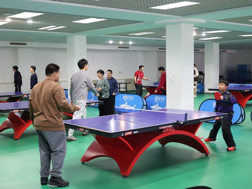 Summer Camp at an International School: What to Expect 1 Lower school students actively playing table tennis in a modern indoor sports facility during a structured enrichment session