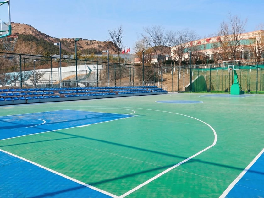 Summer Camp at an International School: What to Expect 3 Wide view of a modern outdoor multi-sport complex with basketball courts, bleachers, and fencing on an international school campus in Qingdao