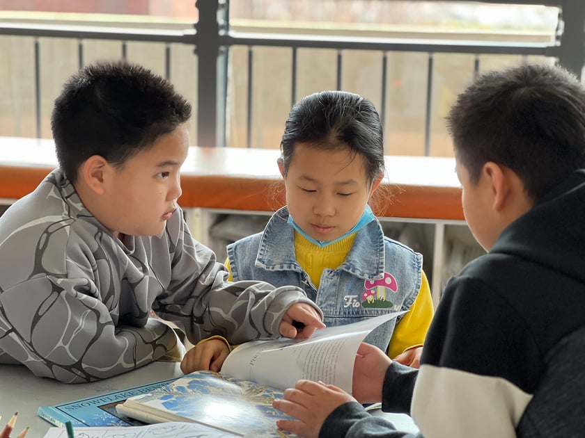 Screen Time and Students: What the Research Shows 2 Three lower-school students reading and discussing a book together at a classroom table