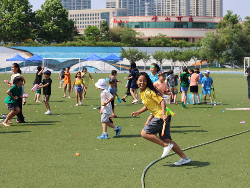 Outdoor Learning Spaces: How Schools Bring Nature In 3 Lower school students playing outdoor games on a grass field supervised by teachers