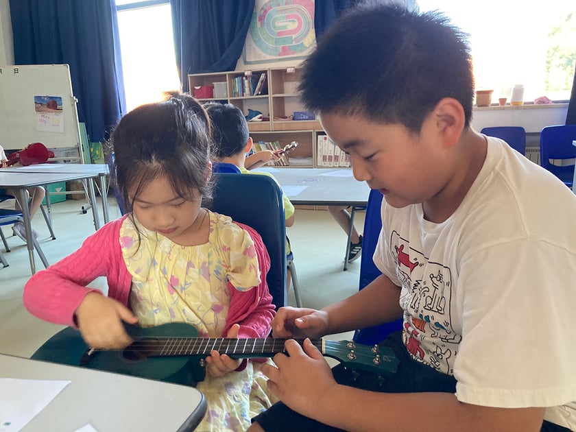 Parent-Teacher Conferences: How to Make Them Count 2 Teacher guides young student one-on-one in a bright QISS classroom setting