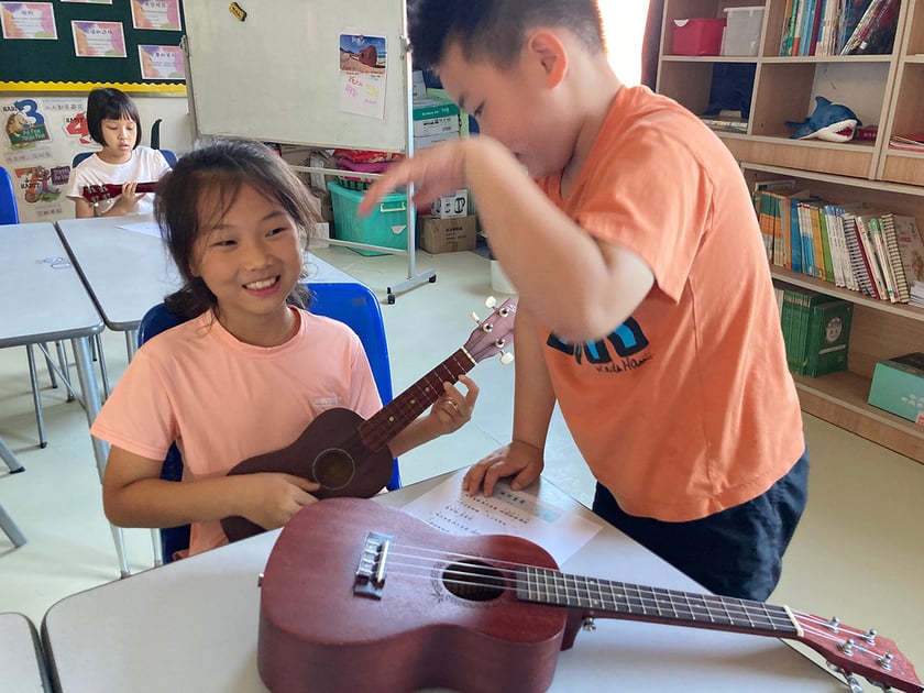 Parent-Teacher Conferences: How to Make Them Count 3 Teacher and smiling student share a moment during one-on-one ukulele instruction at QISS