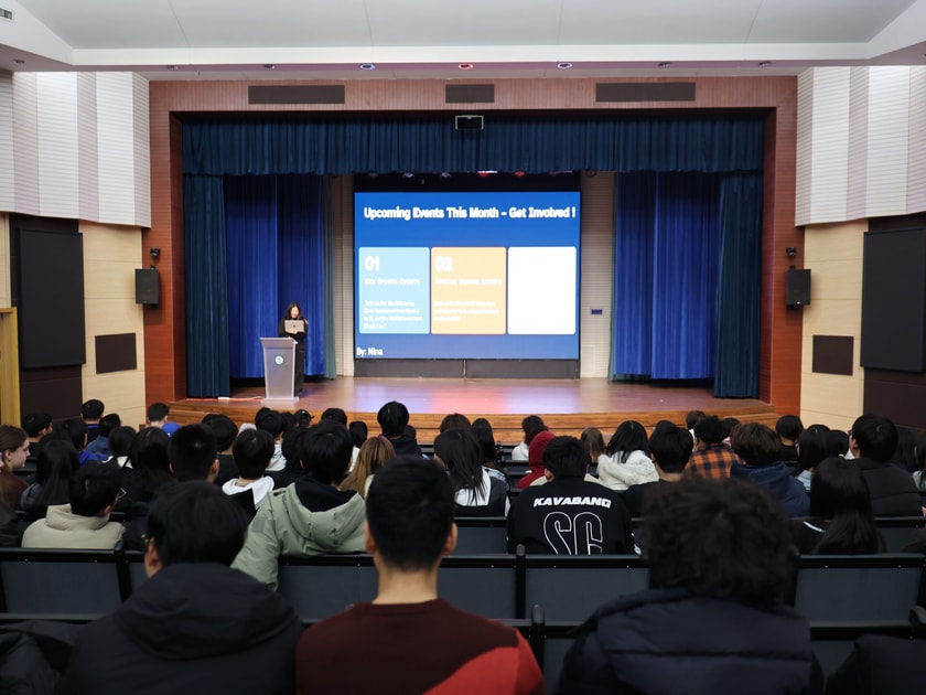 Middle school students in auditorium viewing upcoming events slide during school assembly at QISS