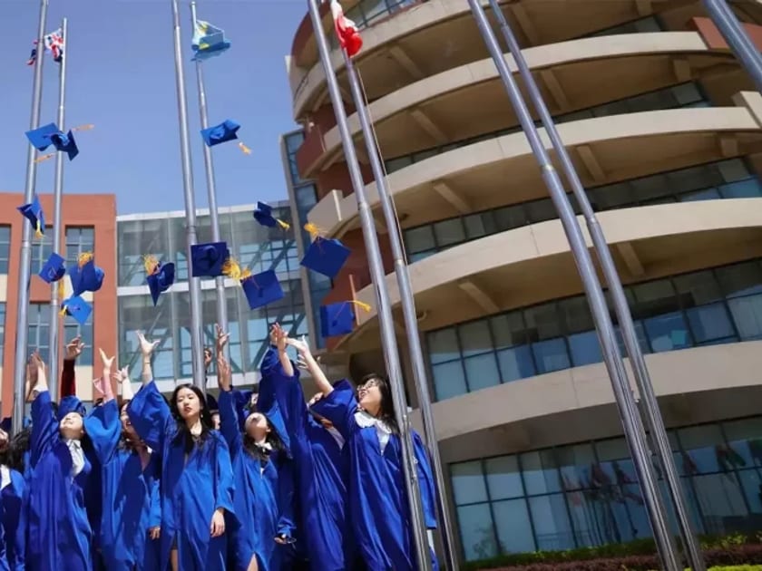 Applying to Australian Universities from China: What Students Should Know 1 QISS graduates in blue robes throw their caps in the air in front of campus buildings