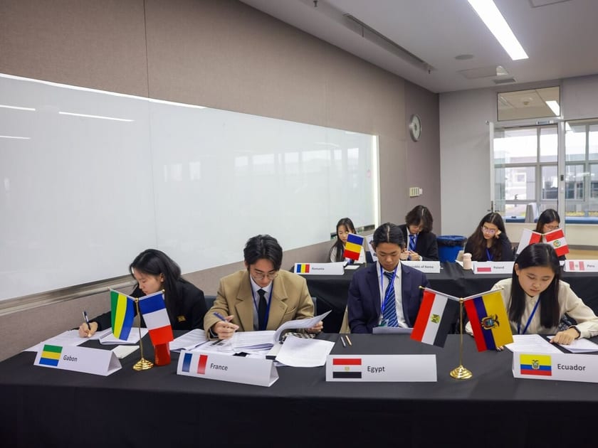 Applying to Universities in Europe from China: A Guide for International School Students 1 High school students in blazers read papers at a Model UN session behind country placards for France, Egypt and Ecuador