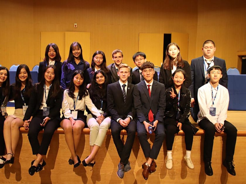 Applying to Universities in Japan from China: A Guide for International School Students 2 A group of QISS high school students in formal attire sit together on a stage at a Model UN conference