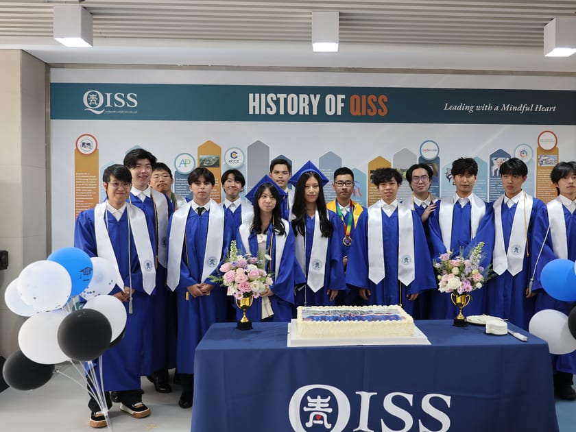 Early Action vs Early Decision: What Students in China Should Know 1 QISS graduates in blue gowns and white stoles stand in front of the History of QISS wall with a celebration cake