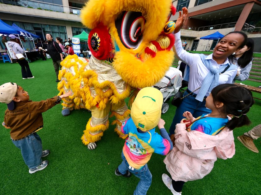 International Kindergartens in China: A Parent's Guide 3 Young children reach out to a yellow lion dance costume during International Day on the QISS campus