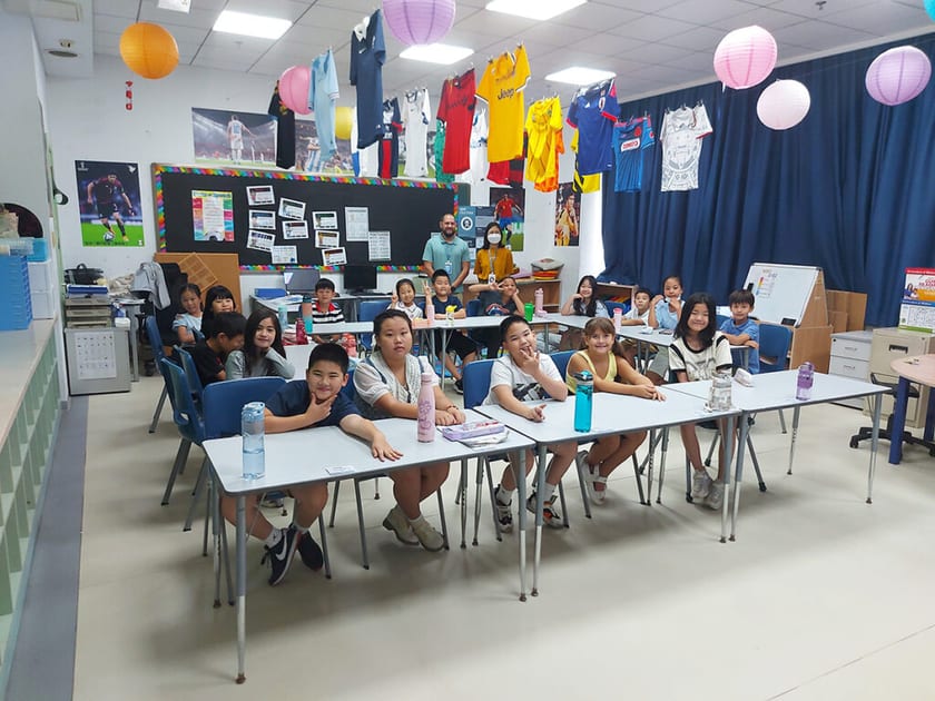 The Chinese School System Explained: Grades, Ages and US Grade Equivalents 1 Primary students sit at classroom desks with two teachers standing behind them under hanging paper lanterns and football shirts