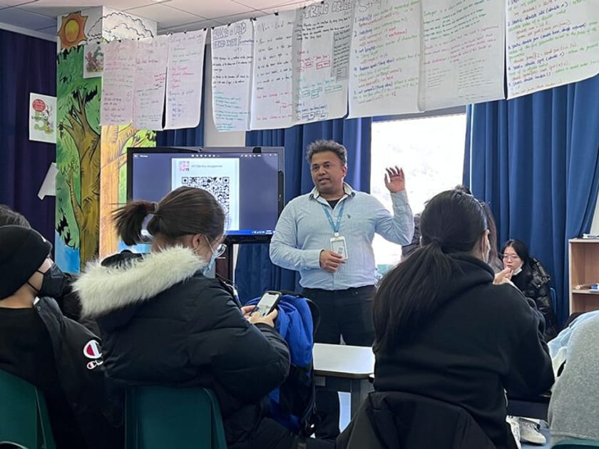 The SAT Chinese Subject Test: What Happened to It and What Students Take Instead 1 A teacher in a light blue shirt talks with high school students seated around tables in a QISS classroom hung with student work